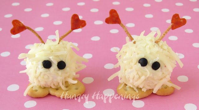 mini cheese ball warm fuzzies with black olive eyes, cracker feet, and pepperoni and chow mein noodle antennae. 