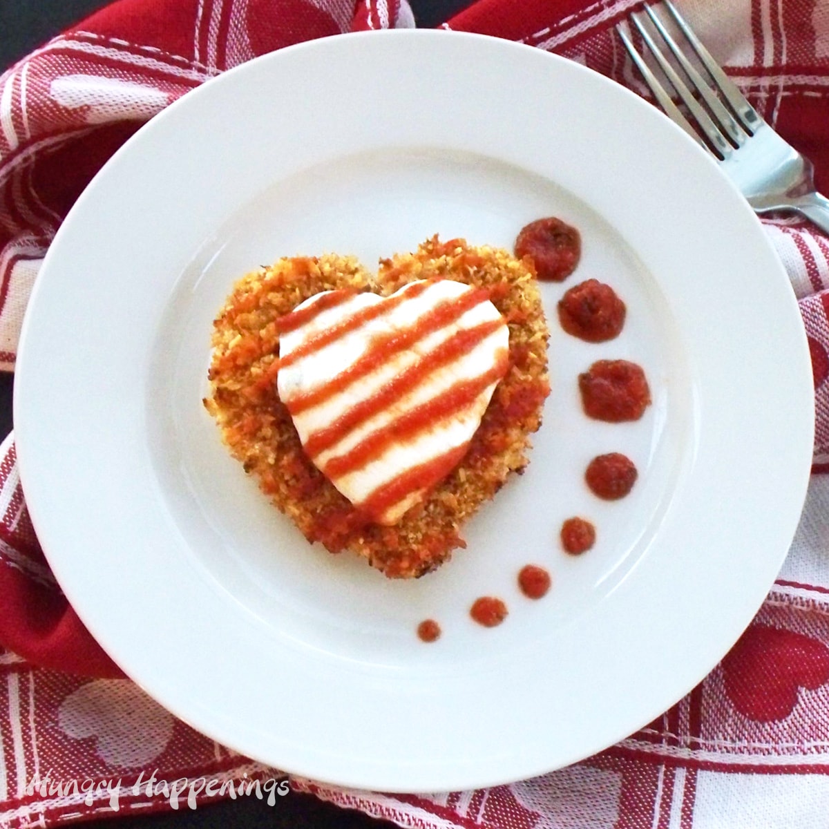 Chicken Parmesan Hearts topped with fresh mozzarella cheese and marinara sauce served on a Valentine's day cloth napkin. 