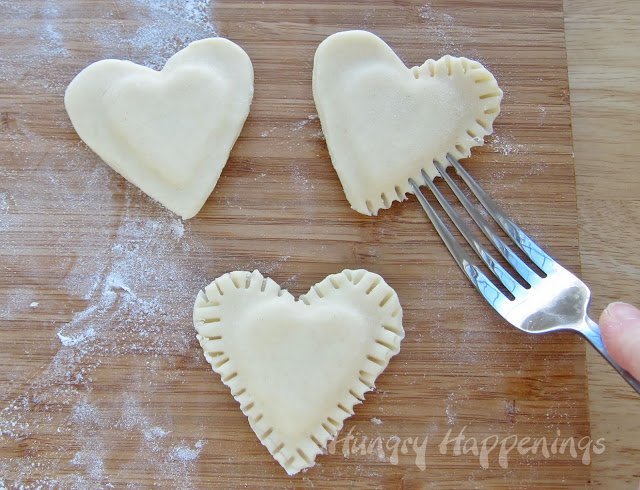 crimp edges of heart-shaped pastries using a fork