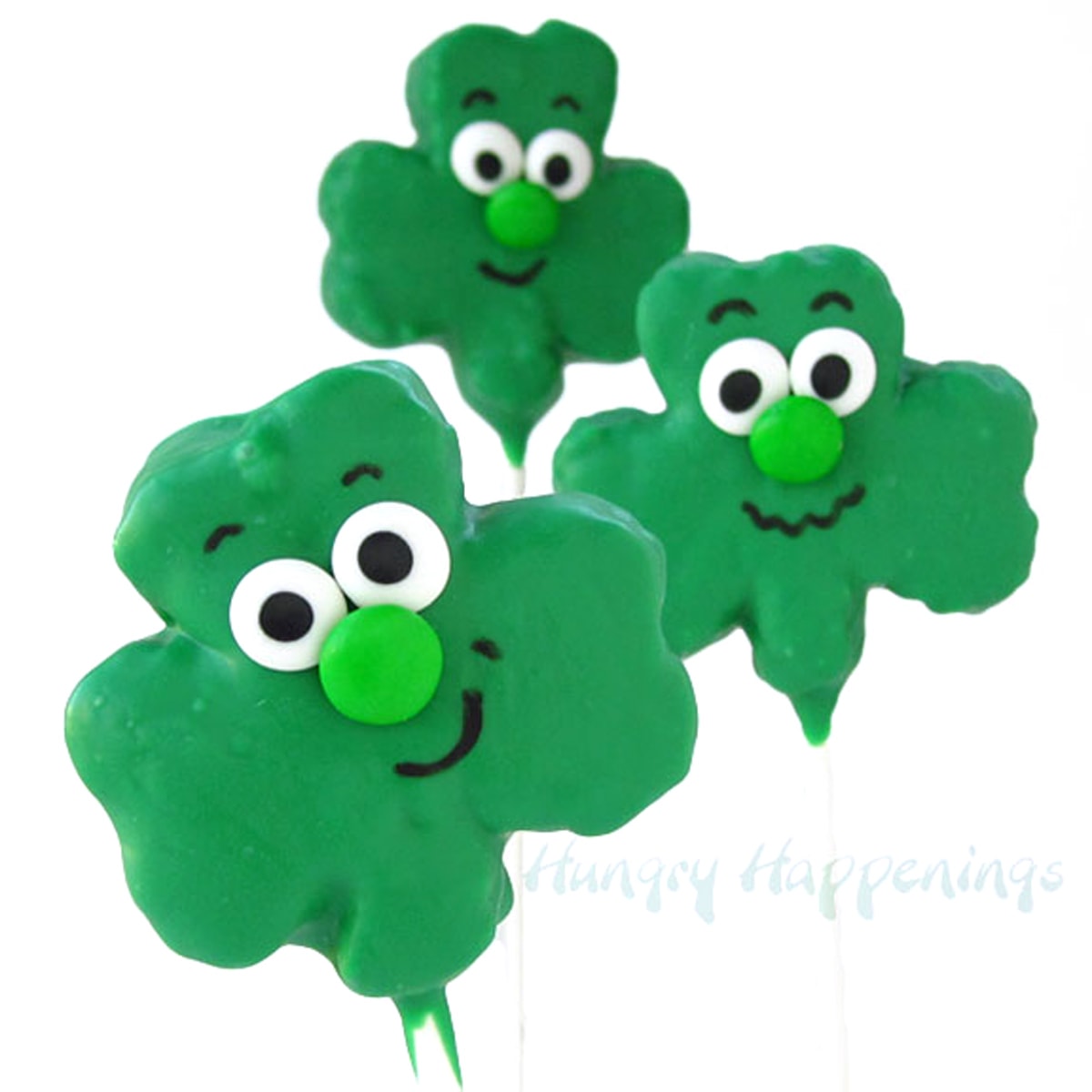 White chocolate coated shamrock rice krispie treat pops with cute smiley faces.