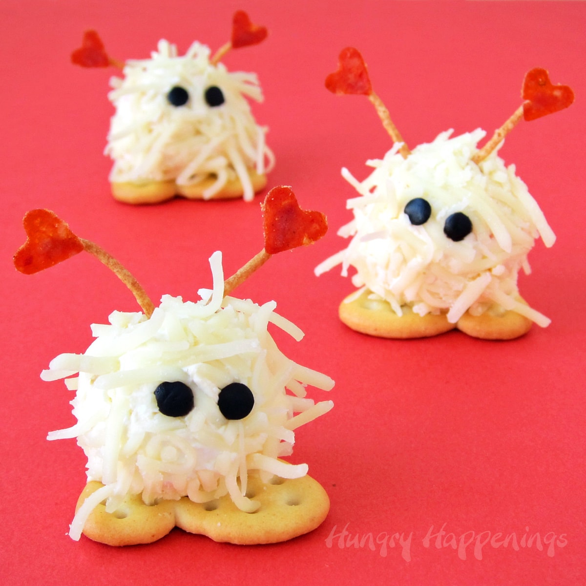 mini Valentine's Day appetizer cheese ball warm fuzzies with heart-shaped pepperoni antenna, olive eyes, and cracker feet