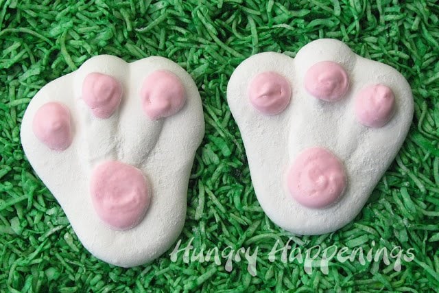 two pink and white marshmallow bunny feet on green-colored coconut grass. 