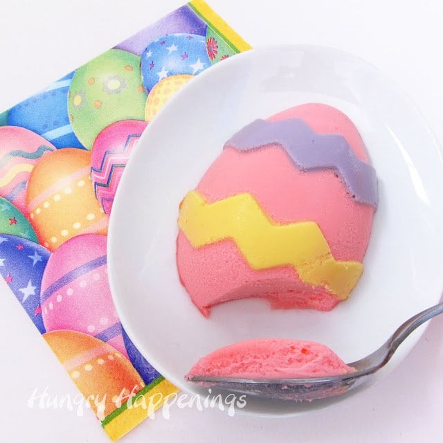 1 pink hand-painted cheesecake Easter egg served on a white egg-shaped plate on top of an Easter egg napkin. 