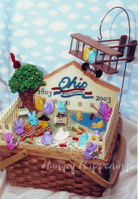Ohio bicentennial basket filled with Peeps having a picnic, fishing, working on a farm, and more arranged on Rice Krispie treat hay with a candy buckeye tree and peeps flying in a chocolate Wright B Flyer. 
