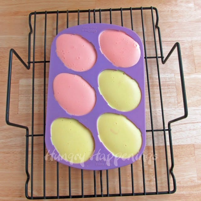 baked cheesecake eggs in a silicone mold that is cooling on a wire rack. 