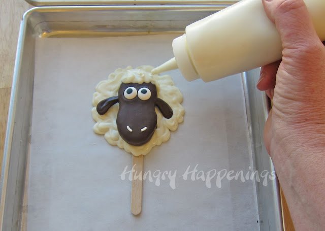 piping white chocolate wool over the chocolate lamb's head. 
