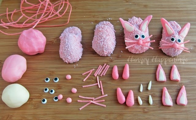 decorating pink bunny slipper cookies with modeling chocolate noses and ears, edible Easter grass whiskers, and candy eyes. 