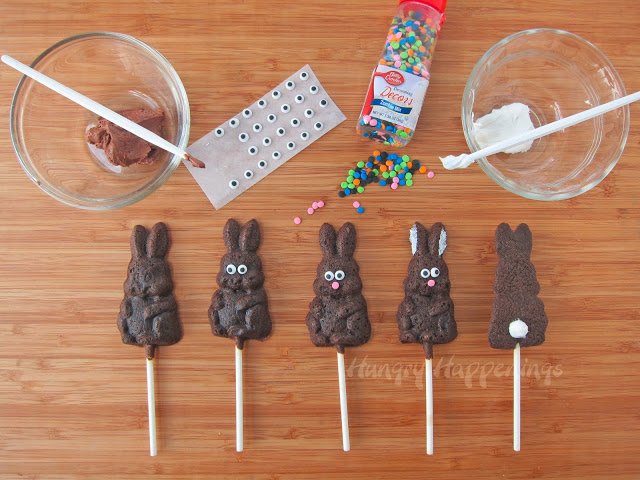 decorating chocolate bunny cookies with candy eyes, pink confetti sprinkle noses, and white chocolate tails. 