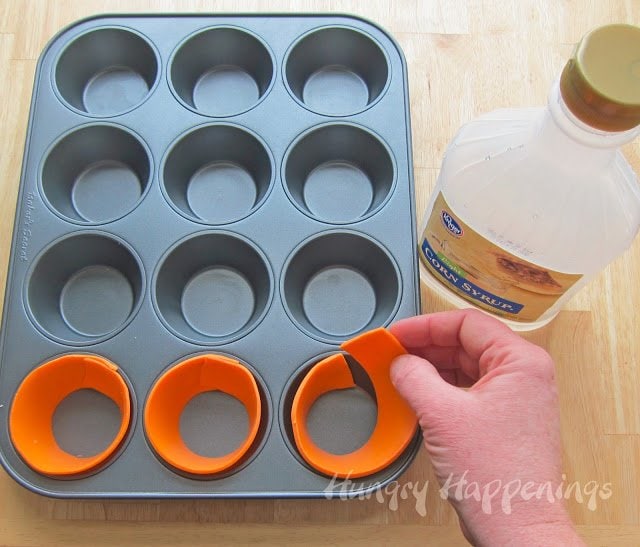 lining cupcake cavities in a non-stick pan with orange modeling chocolate cupcake wrappers. 