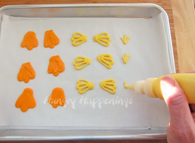piping yellow feathers, wings, and orange feet for white chocolate chickens. 