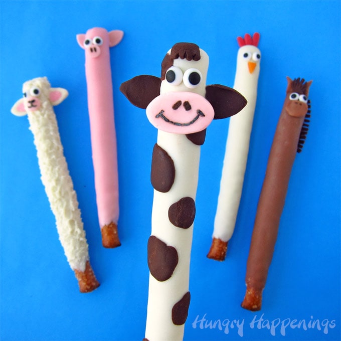 Chocolate-dipped pretzel farm animals including a sheep, pig, cow, chicken, and a horse.
