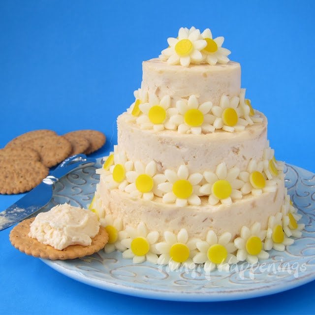 Cheese ball cake decorated with yellow daisies made out of cheese.