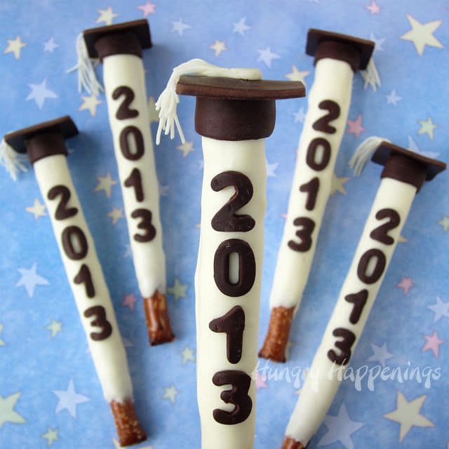 Graduation Pretzel Pops decorated with modeling chocolate grad caps and date.
