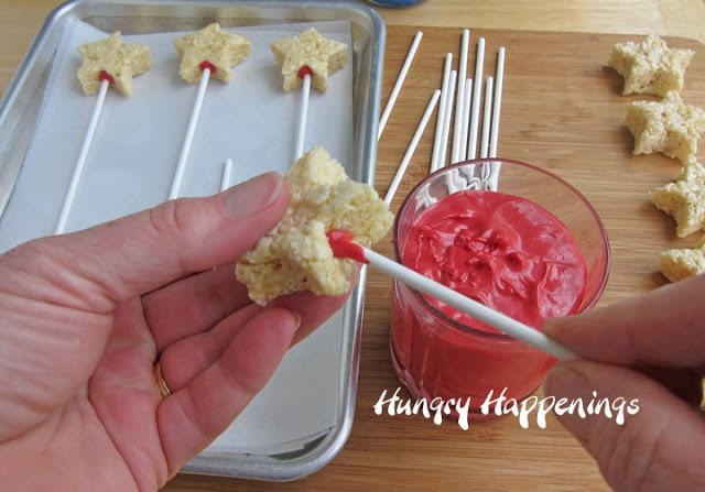 Adding a lollipop stick to a rice crispy treat star using red candy melts.
