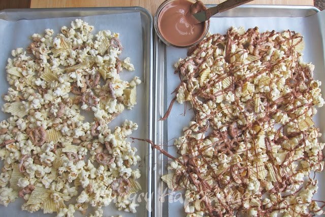 drizzling chocolate over white chocolate popcorn filled with potato chips, peanuts, and pretzels. 