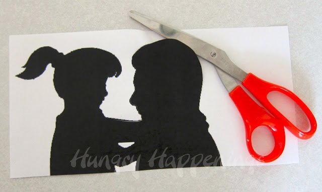 cutting out a silhouette of a little girl and her dad. 