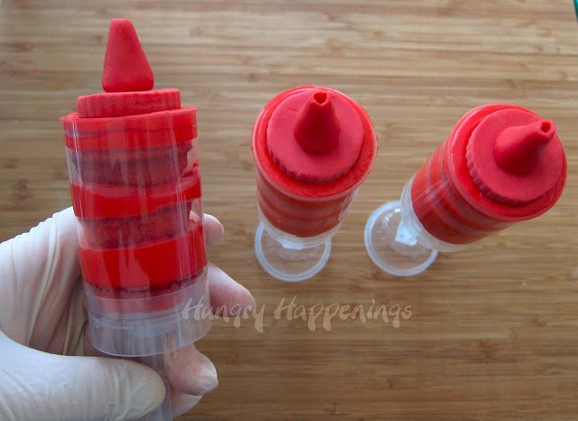 3 red push-pops that are decorated to look like ketchup bottles. 