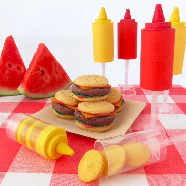 picnic table with watermelon, hamburger ice cream sandwiches, ketchup and mustard push pops. 