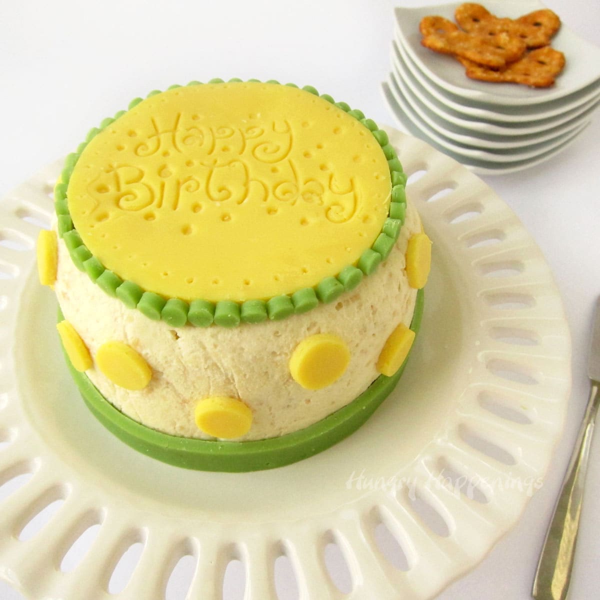 Brightly colored birthday cake cheese ball with yellow polka dots made out of cheese.