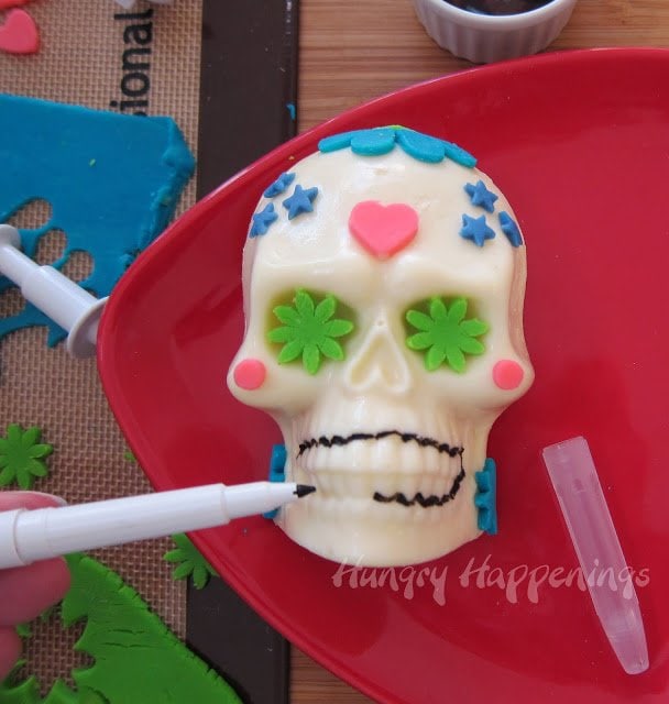 drawing black food coloring around the teeth on a cheese skull.