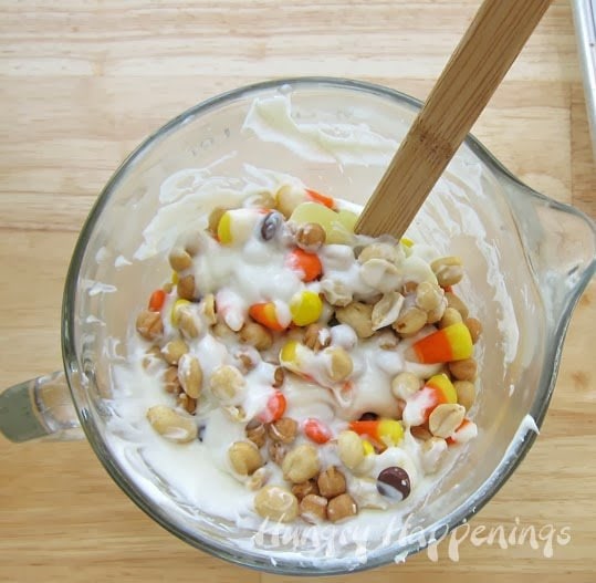 stirring peanuts, candy corn, caramel, Reese's Pieces into a bowl of melted white chocolate. 