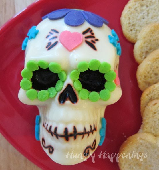 sugar skull made out of cheese with bright green, pink, and blue cheese decorations. 
