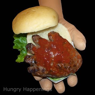Hand-shaped hamburgre on a bun and topped with ketchup. 
