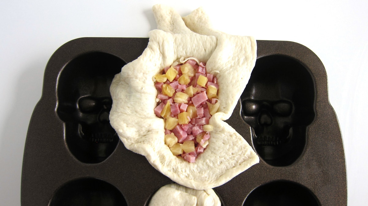 making ham and pineapple pizza skulls using a Nordicware skull pan. 