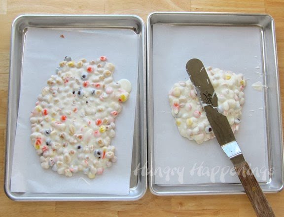 spreading the white chocolate candy corn mixture onto parchment paper-lined baking sheets.