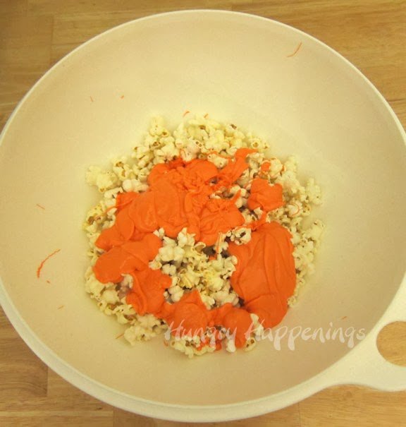 a bowl of popcorn topped with melted orange candy melts. 