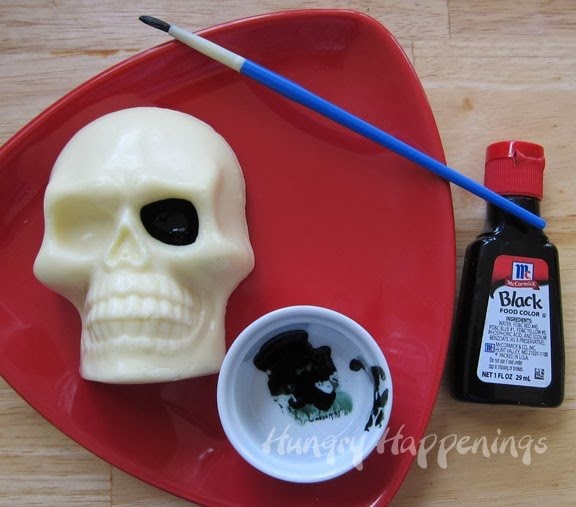 painting black food coloring into the eye socket of the skull-shaped cheese.