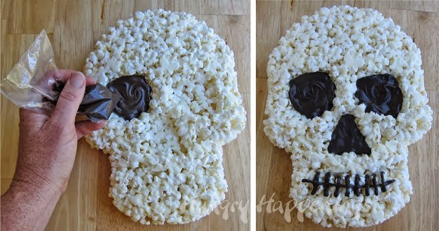 piping chocolate eyes, nose, and mouth onto a white chocolate popcorn skull. 