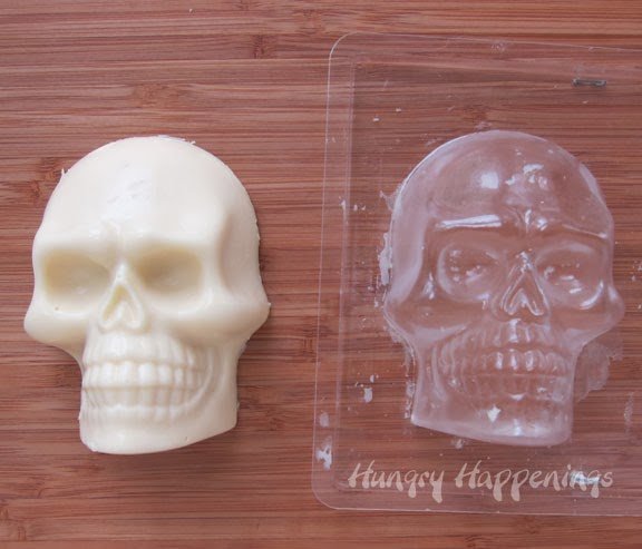 cheese skull on a cutting board next to a plastic skull mold. 