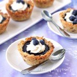 Soft and chewy Coconut Macaroon Cups filed with homemade blueberry curd are topped with a dollop of whipped cream and some fresh blueberries.