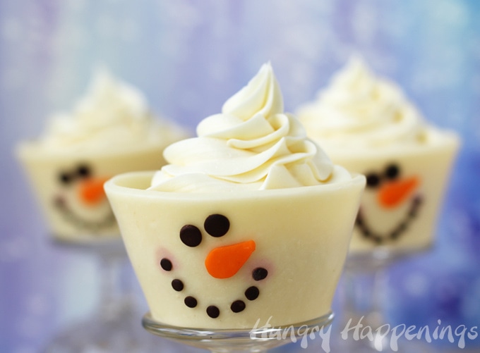 cute Christmas cupcake snowmen are wrapped in white modeling chocolate and have candy eyes and carrot nose