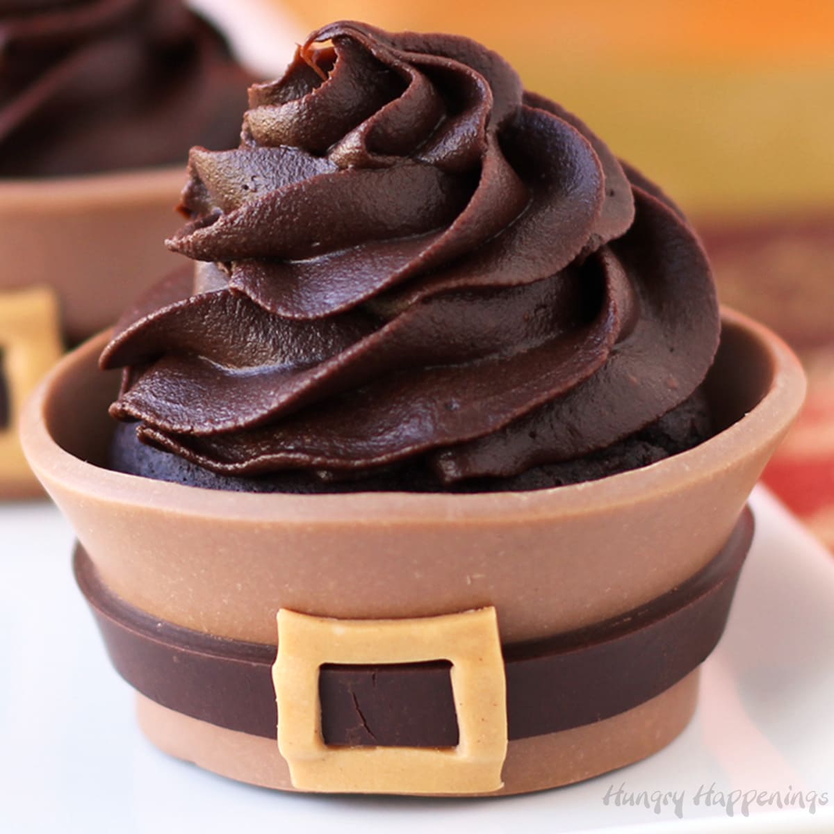 a closeup of a chocolate Thanksgiving cupcake wrapped in a chocolate pilgrim suit and with a big swirl of chocolate frosting on top. 