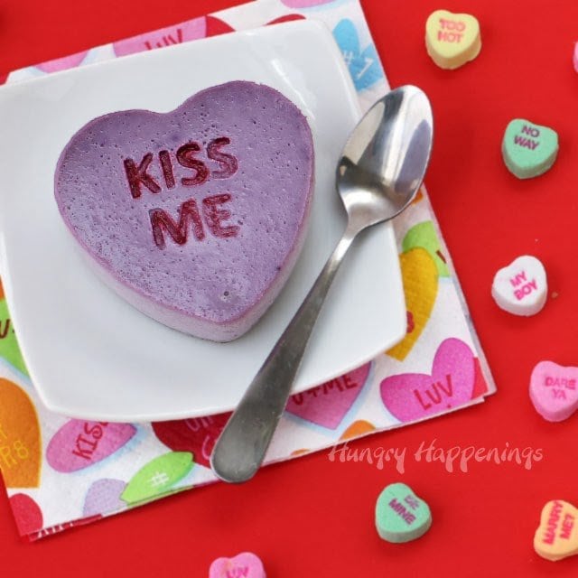 purple conversation heart cheescake imprinted with "KISS ME" and surrounded by conversation heart candies