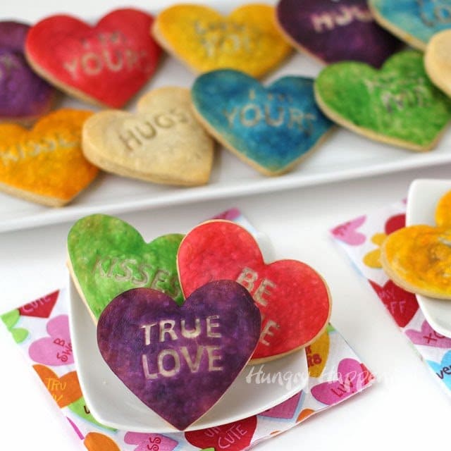 bright and colorful conversation heart pastries arranged on white plates with Valentine's Day napkins.