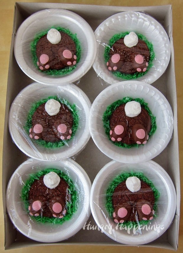 Easter bunny brownies served on green coconut grass in white Styrofoam bowls nestled in a cardboard box. 