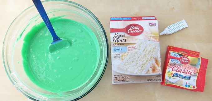 green cake batter in bowl next to a cake mix box