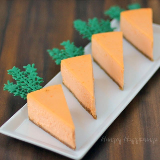 four cheesecake carrots on a white plate on a dark brown wood background