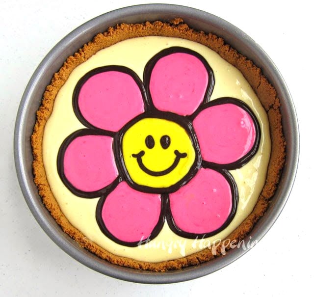 un-baked cheesecake with finished smiley face daisy design on top