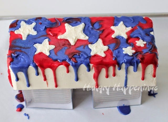 Red, White and Blue drip cake decorated with white frosting stars. 