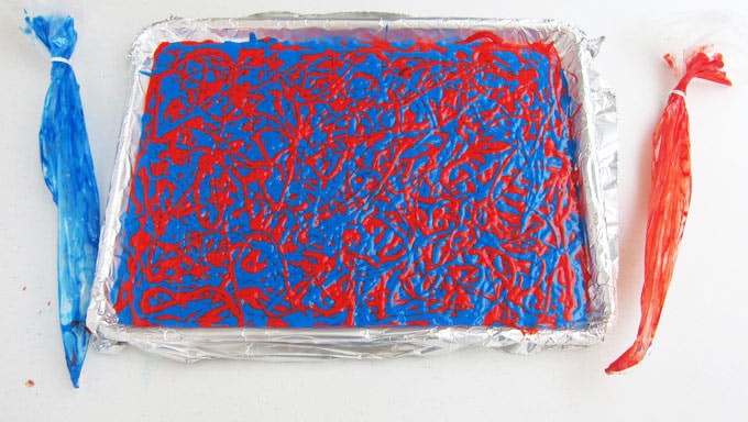 red and blue cake batter piped in swirls in a 13x18