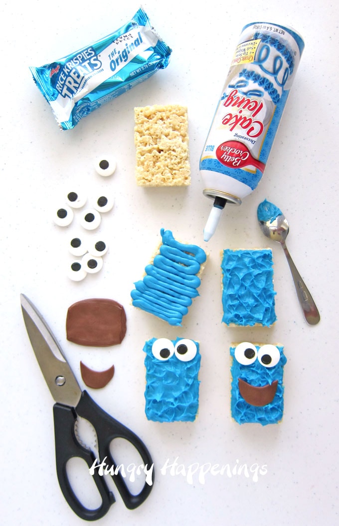 Blue frosting-topped Rice Krispie Treats decorated to look like Cookie Monster using jumbo candy eyes and Tootsie Rolls.