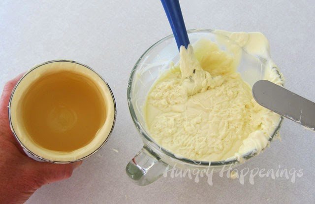 a plastic canister filled with a thick layer of white chocolate next to a bowl of melted white chocolate.