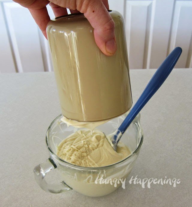 pouring the white chocolate out of the plastic canister into a bowl. 