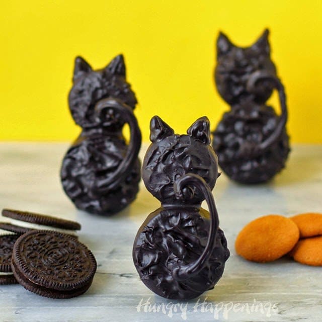 Chocolate dipped black cat cookies next to OREO Cookies and vanilla wafers.