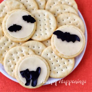 Halloween cheese and crackers with white cheese moons and black Velveeta cheese cats and bats. 