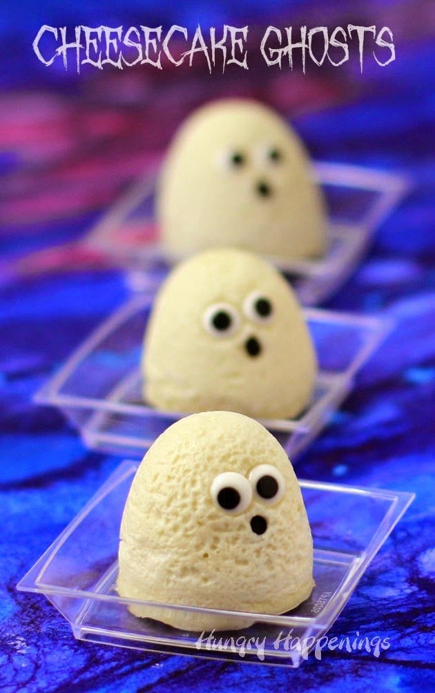 Cheesecake Ghosts with candy eyes served on tiny plastic plate sets on an eerie purple watercolor table covering